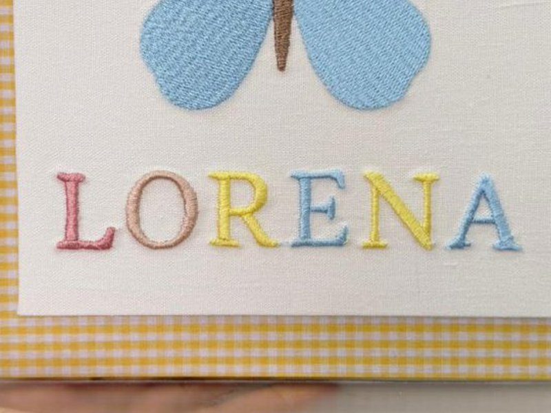 O nome LORENA bordado por inteiro em letra bast�o, cada letra numa cor - rosa, bege, amarelo e azul