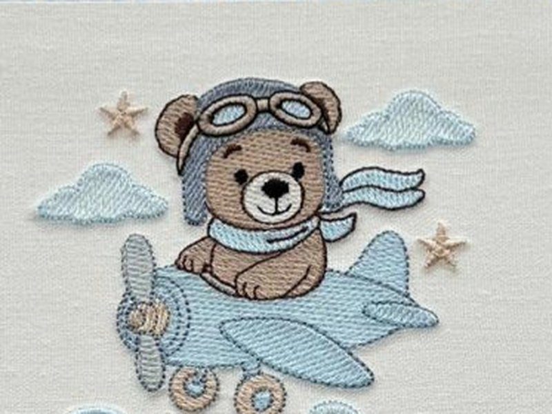 Ursinho marrom com touca e �culos de aviador pilotando um avi�o azul-claro, com cachecol ao vento