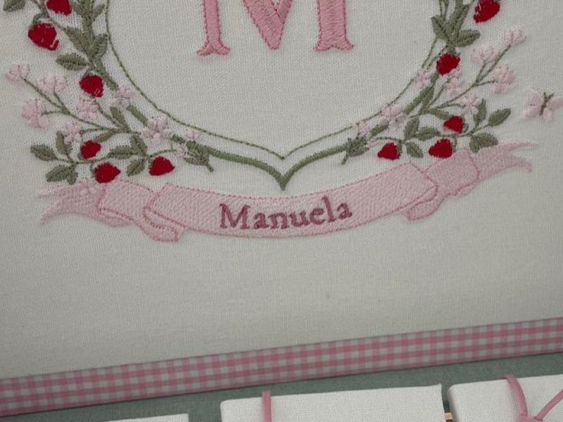 Faixa rosa bordada com Manuela em letra serifada