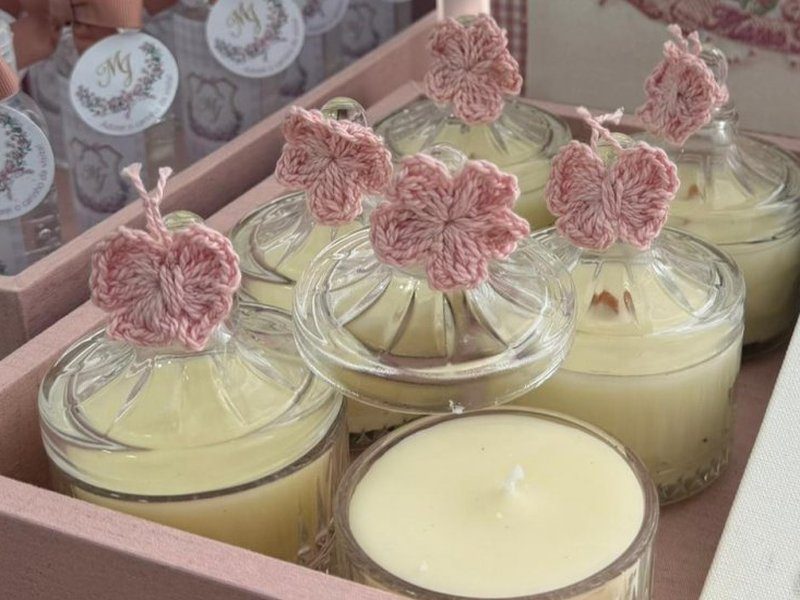 Velas em copo de vidro com flores e borboletas de croch� rosa espetadas no lugar do pavio