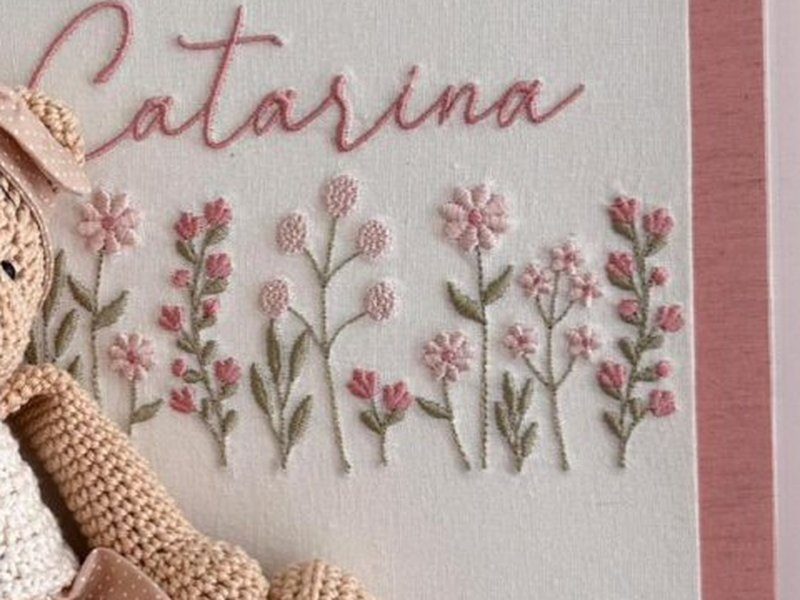 Fileira de flores bordadas rosa e verdes de alturas alternadas sob o nome