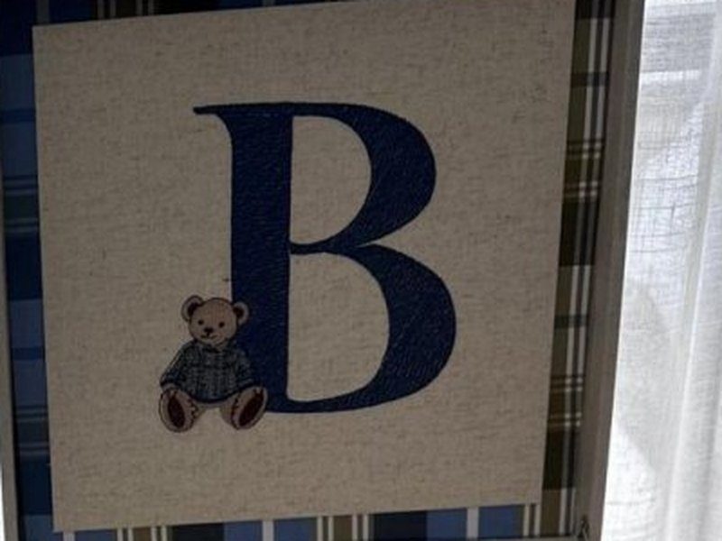 Letra B azul escuro grande com um ursinho bordado sentado encostado na haste