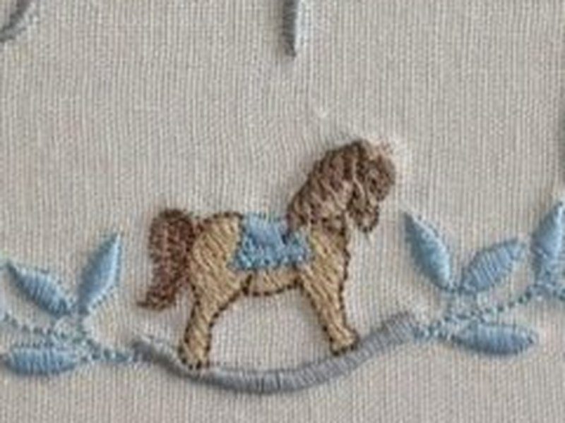 Cavalinho de balan�o bege com sela azul-clara, na base da coroa de folhas azuis