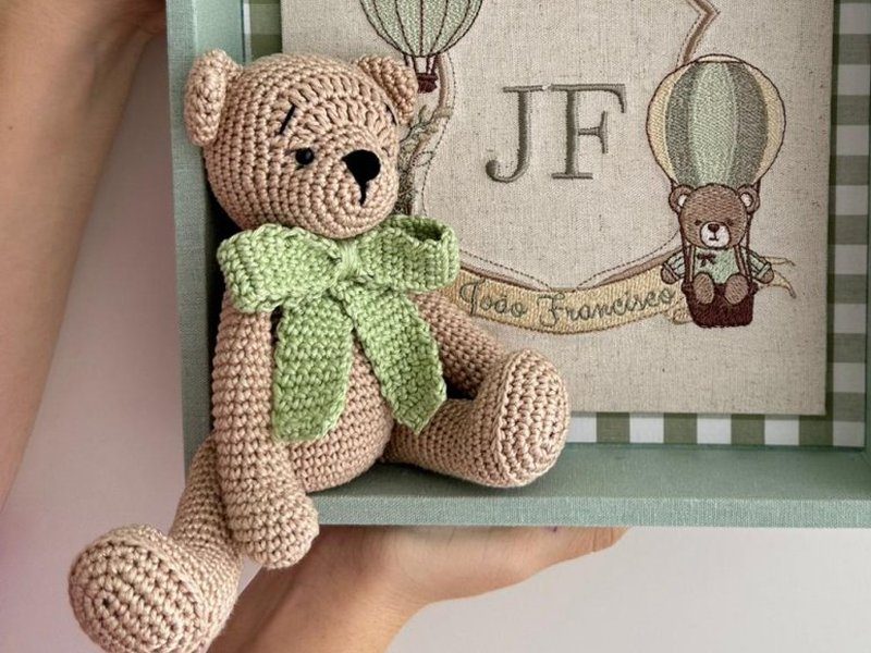 Urso de croch� sentado, com gravata de croch� verde, dentro da caixa-moldura