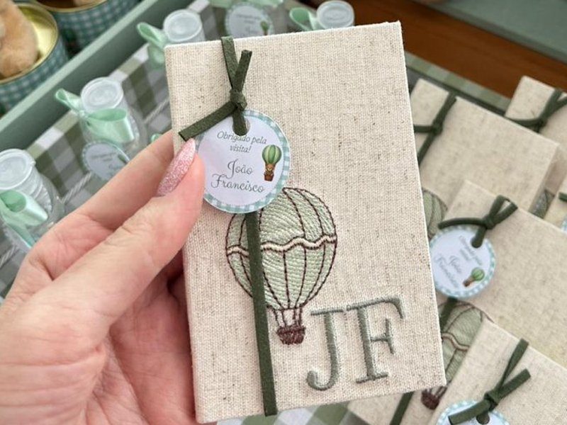 Capa de linho com bal�o de ar quente bordado e JF em verde, com fitilho de camur�a e tag