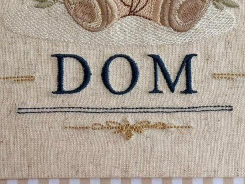 O nome DOM em caixa alta azul escuro com o filete e o arabesco dourado logo abaixo
