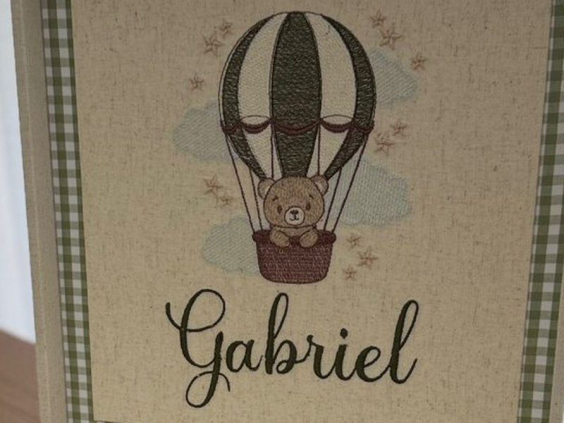 Bal�o de ar quente bordado em verde levando um ursinho na cesta, entre nuvens e estrelinhas, com o nome Gabriel em cursiva embaixo