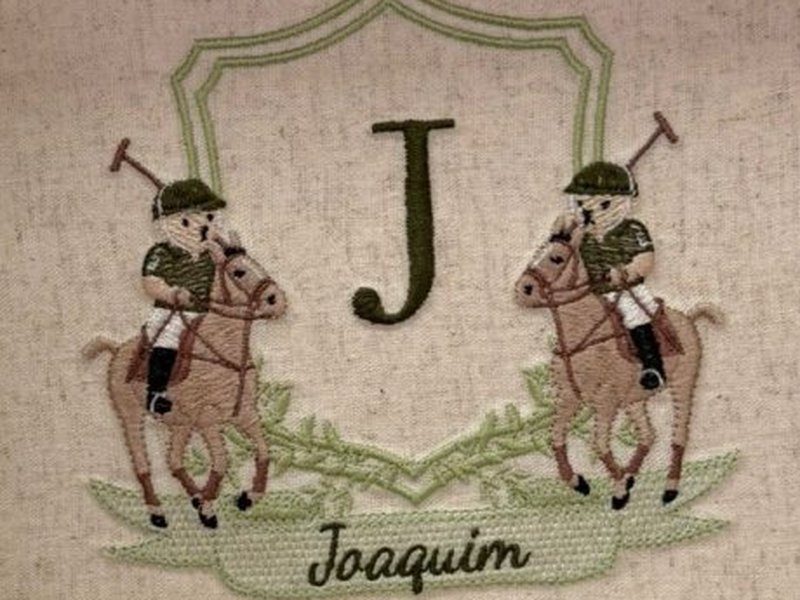 Os dois jogadores de polo bordados, espelhados, com tacos erguidos, ladeando a letra J