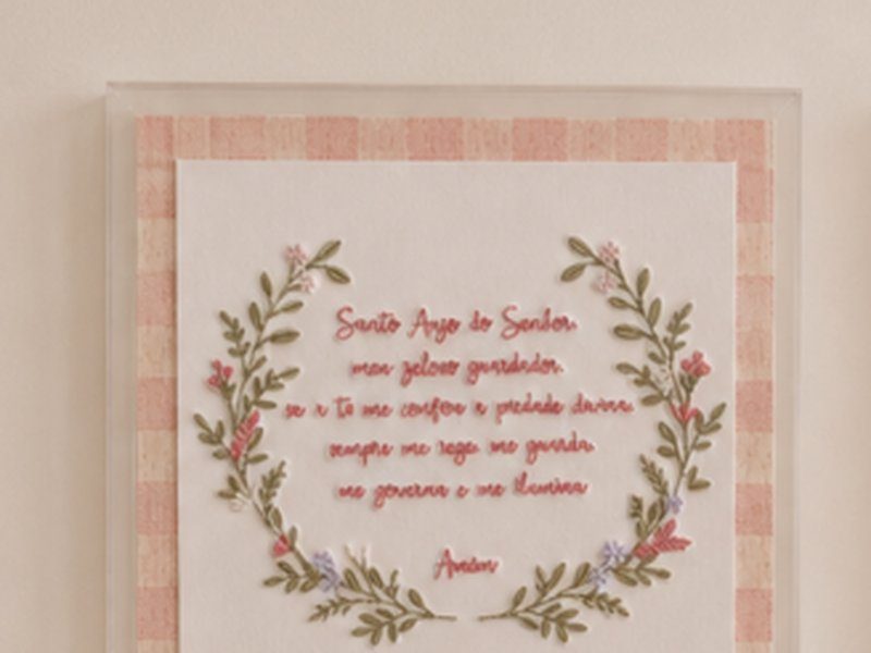 A ora��o Santo Anjo do Senhor bordada em cursiva dentro de uma guirlanda de flores e folhas