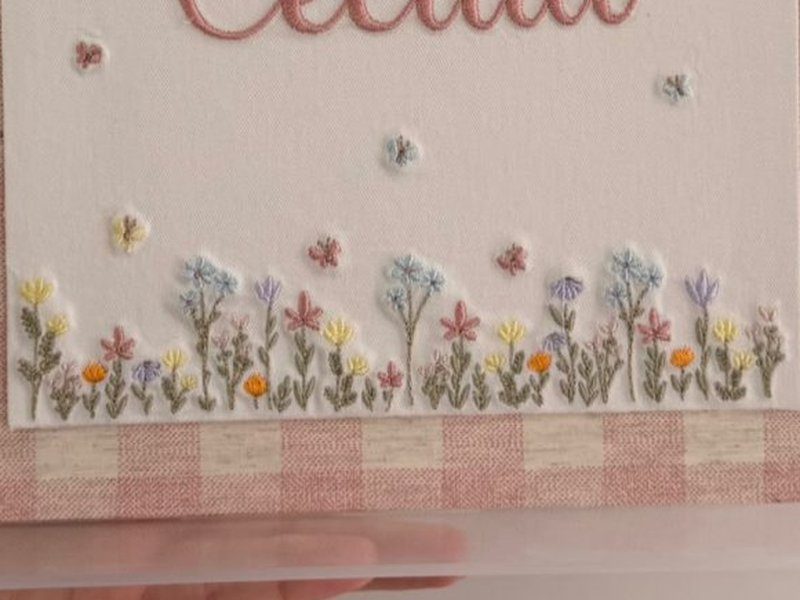 A faixa de flores do campo bordadas em azul, lil�s, amarelo, laranja e rosa ao longo da base