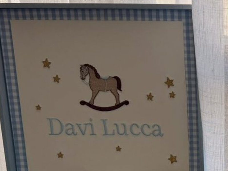 Cavalinho de balan�o bordado na tampa com o nome Davi Lucca embaixo e estrelas de madeira aplicadas ao redor