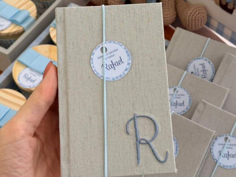 Moleskine de capa dura de linho com a letra R bordada em azul no canto inferior direito e el�stico azul fino