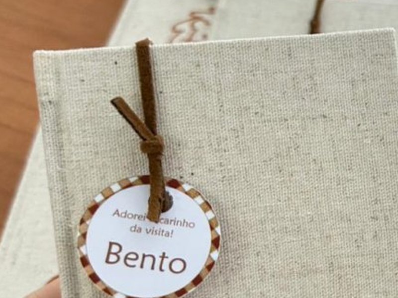 N� do cord�o de suede marrom com a tag de borda xadrez e o nome Bento