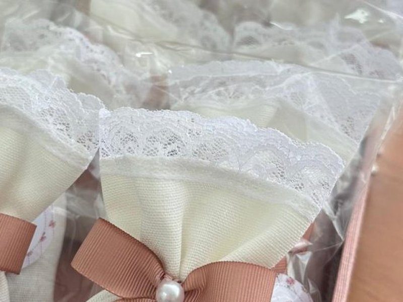 Os sach�s de cetim creme com barra de renda embalados um a um em saquinho de celofane transparente